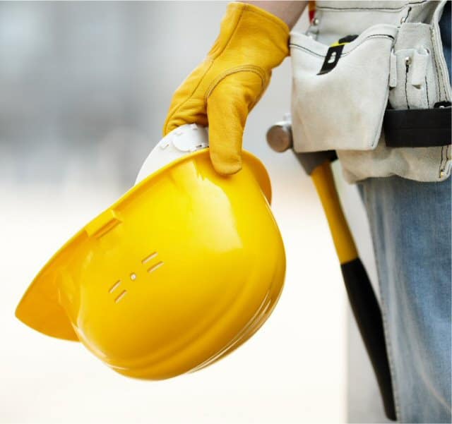 workers hand holding a yellow hard hat