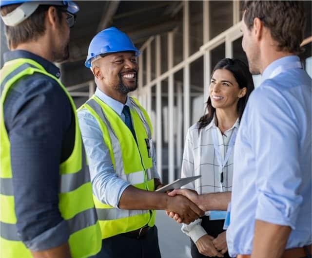 Three men and a woman shaking hands on a construction site